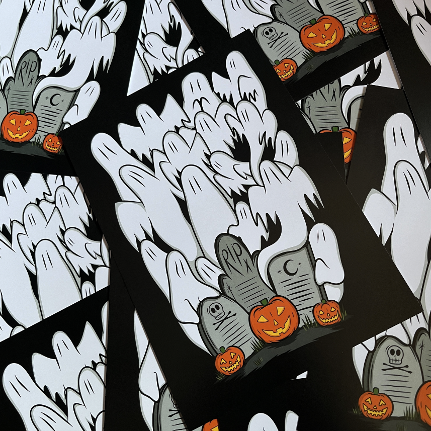 A close-up of overlapping rectangular prints or cards featuring a Halloween illustration: white ghostly hands rising from black ground, gray tombstones, and orange jack-o'-lantern pumpkins.