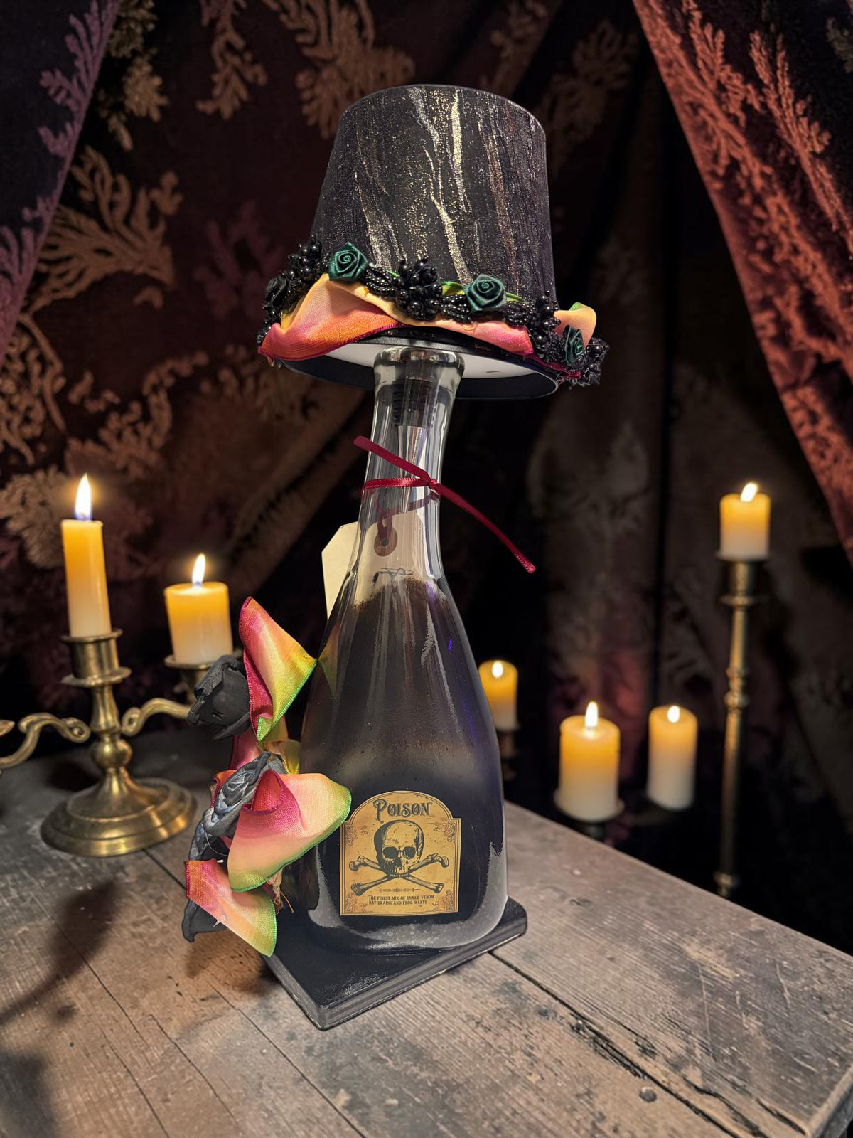 Halloween-Emporium Couture Poison bottle lamp with a black marbled shade, skull label, and colorful decorative bow.