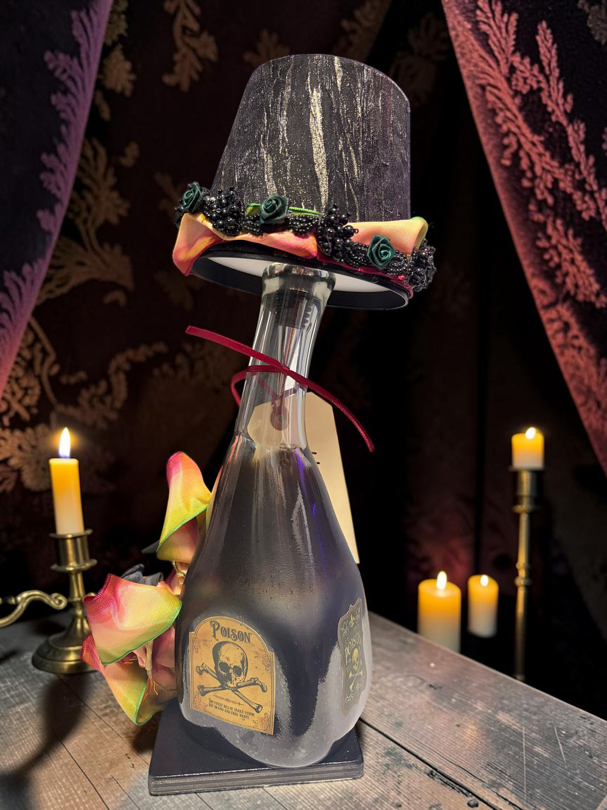 Halloween-Emporium Couture Poison bottle lamp with a black fabric shade, skull label, and colorful ribbon accents.