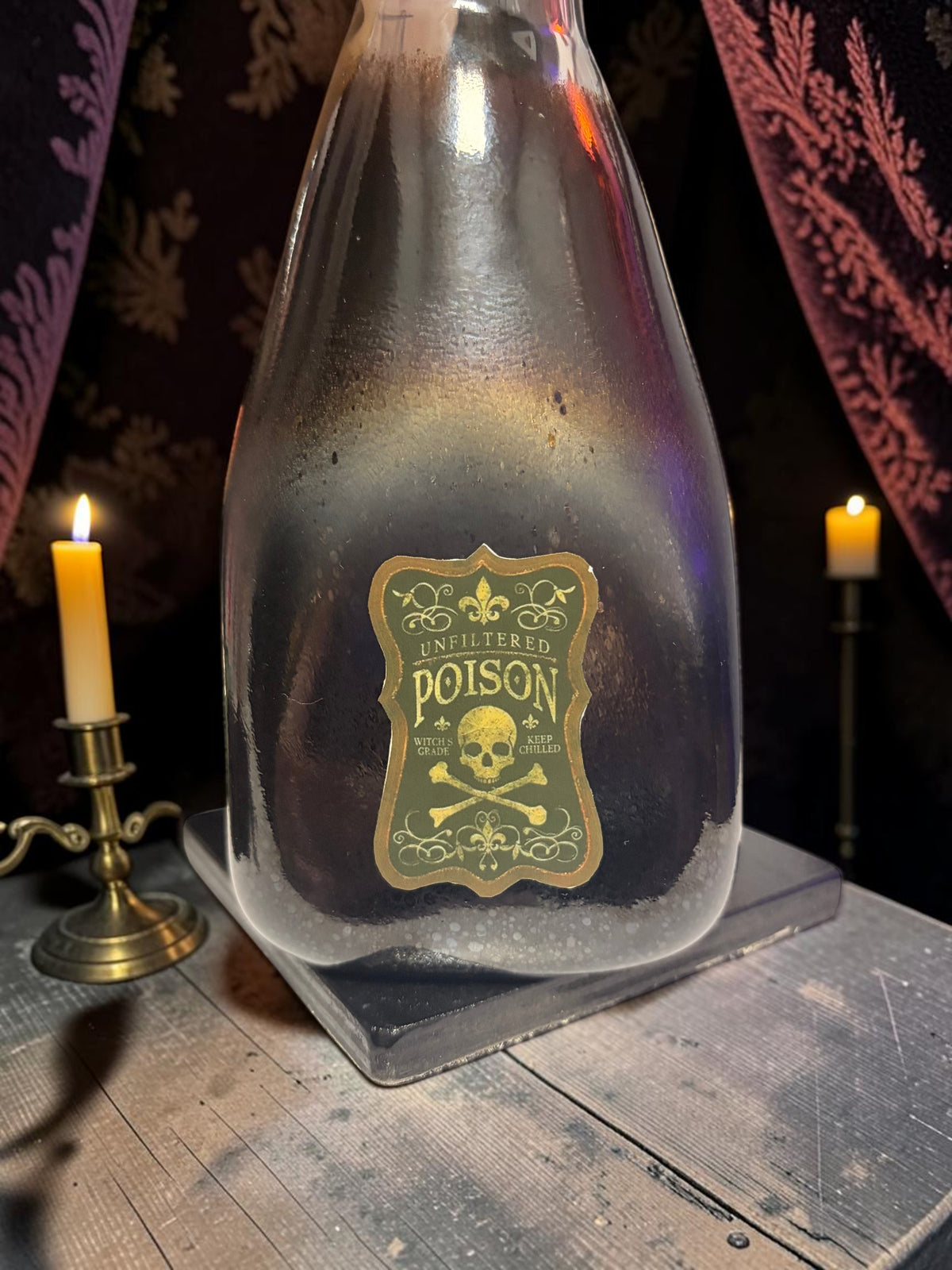 Halloween-Emporium Couture Poison bottle lamp with a dark glass finish and a vintage skull and crossbones label