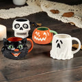 Halloween-Emporium set of four 3-D ceramic Halloween mugs featuring a black cat, white ghost, skull, and pumpkin.