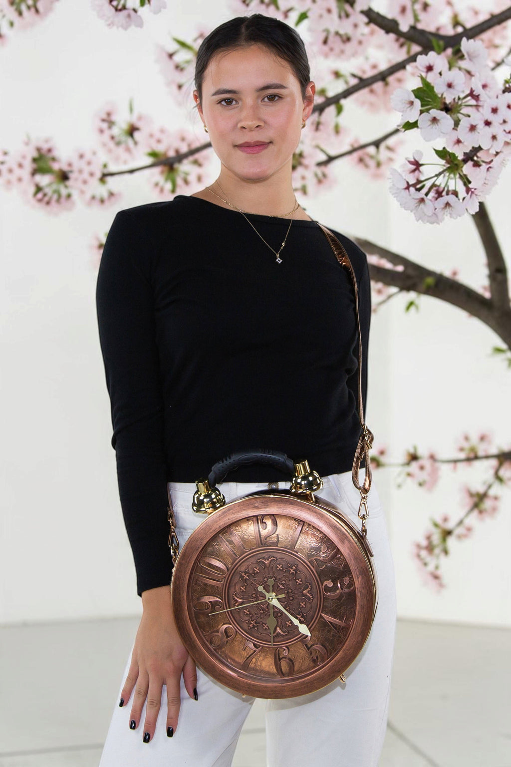 Halloween-Emporium antique clock bag in copper-toned vinyl worn by a model against a cherry blossom background