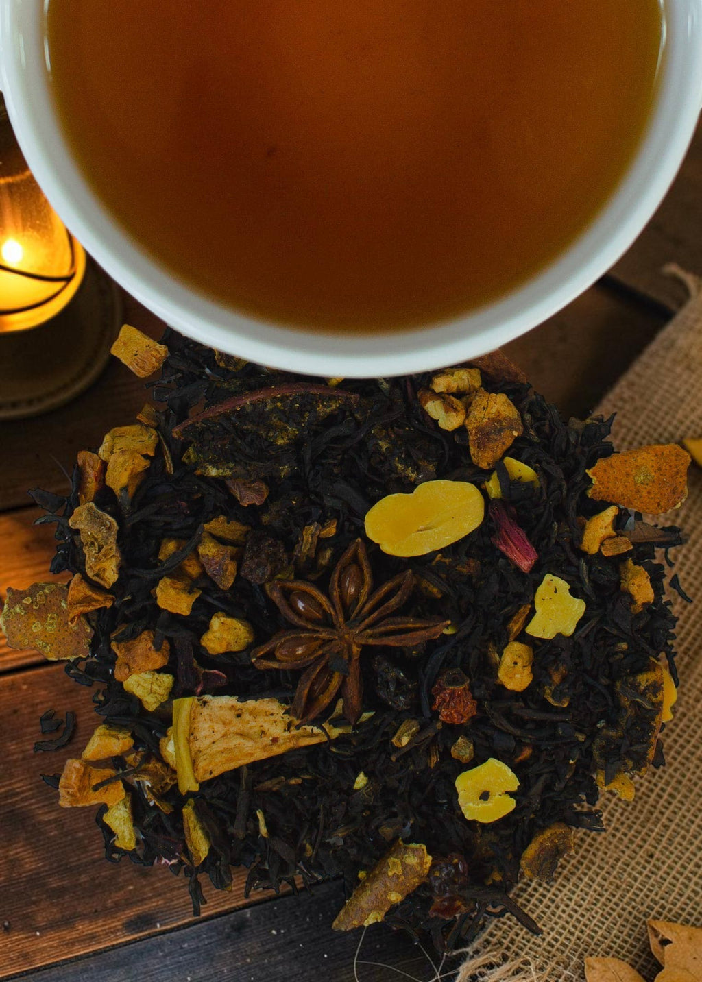 Halloween-Emporium Apple Cider Halloween black tea blend with dried apple, star anise, and nuts next to a warm cup.