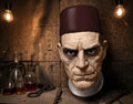 Halloween-Emporium Universal Classic Monsters Ardeth Bey latex mummy mask with a deep red fez hat in a tomb setting.