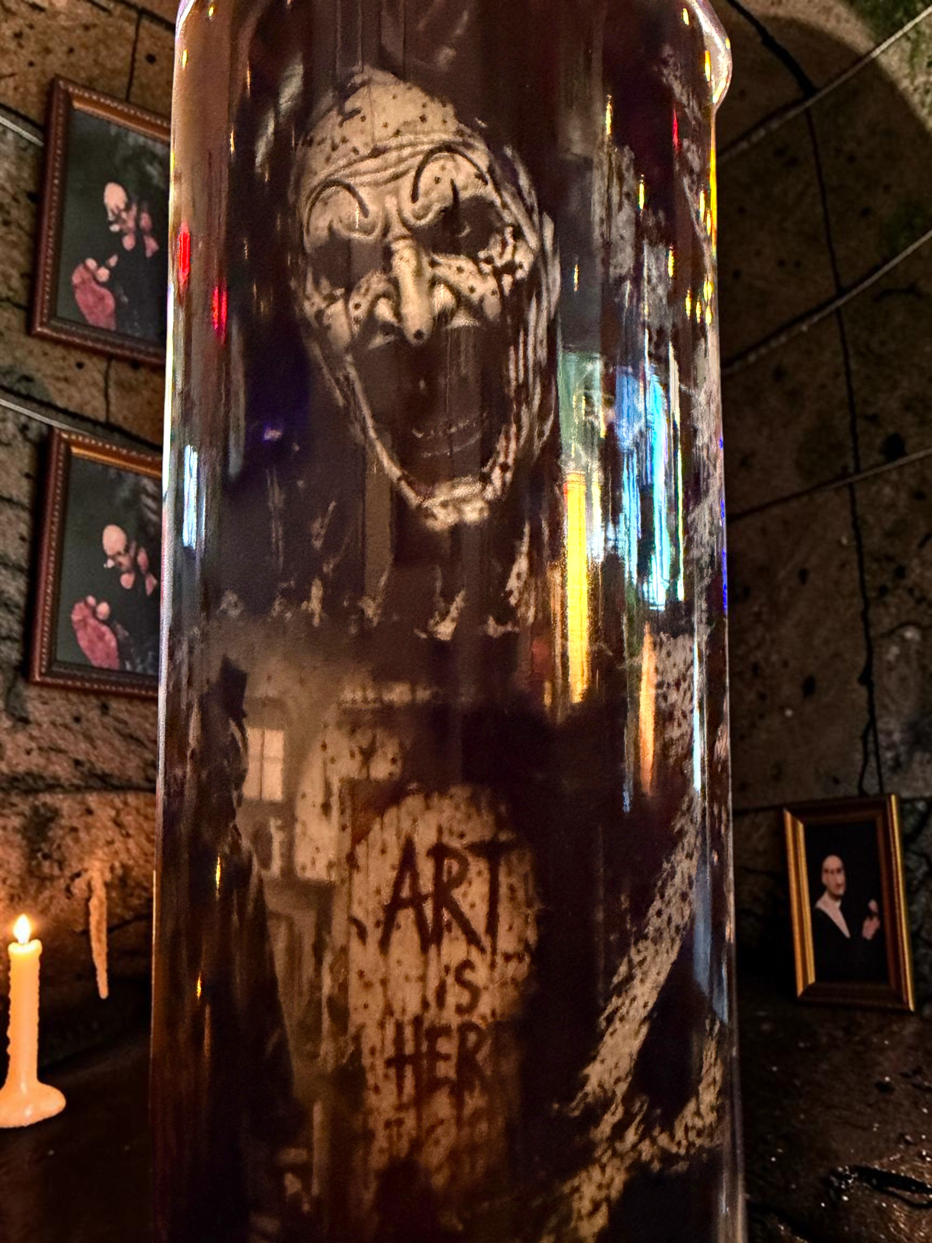 Halloween-Emporium 30oz tumbler featuring a dark Art the Clown graphic design in a gothic candlelit setting