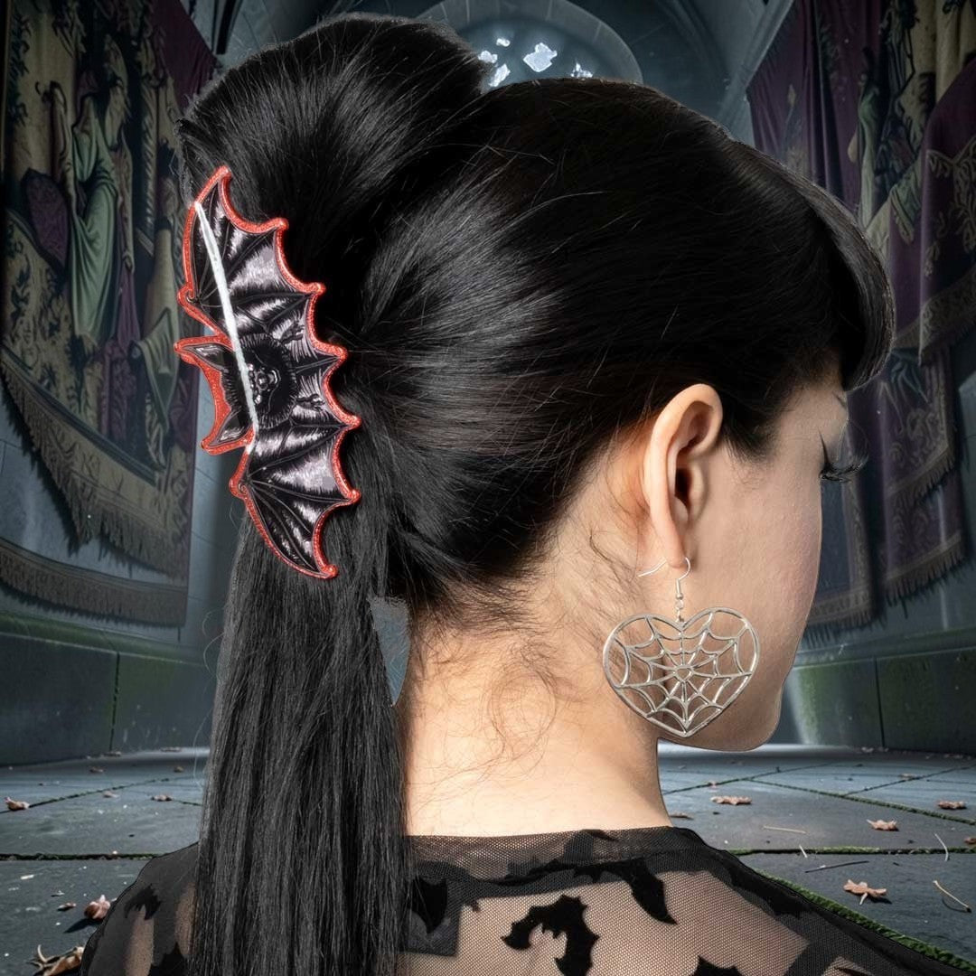Halloween-Emporium bat-shaped claw clip with red glitter border worn in black hair against a gothic backdrop