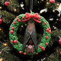 Halloween-Emporium bat ornament featuring a brown bat hanging inside a green holiday wreath with red berries and a bow.