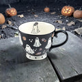 Halloween-Emporium 16oz black ceramic latte mug with white ghost and floral crown pattern and cream interior