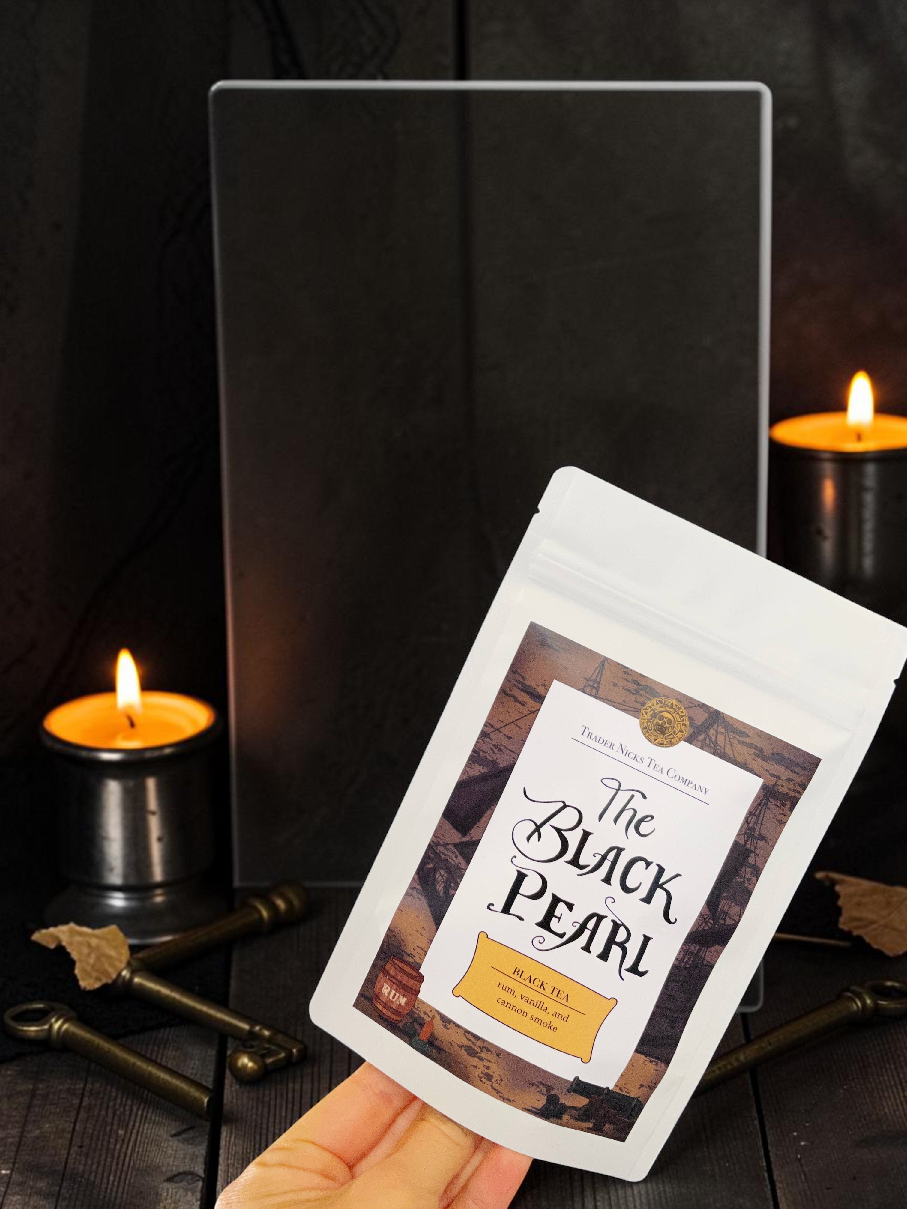 Halloween-Emporium The Black Pearl rum and smoke flavored black tea pouch held against a dark, candlelit pirate backdrop.