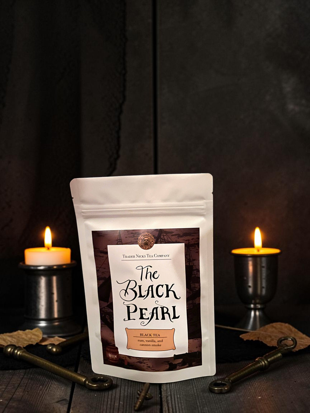 Halloween-Emporium The Black Pearl smoked black tea pouch with rum and coconut notes, displayed with candles and keys.