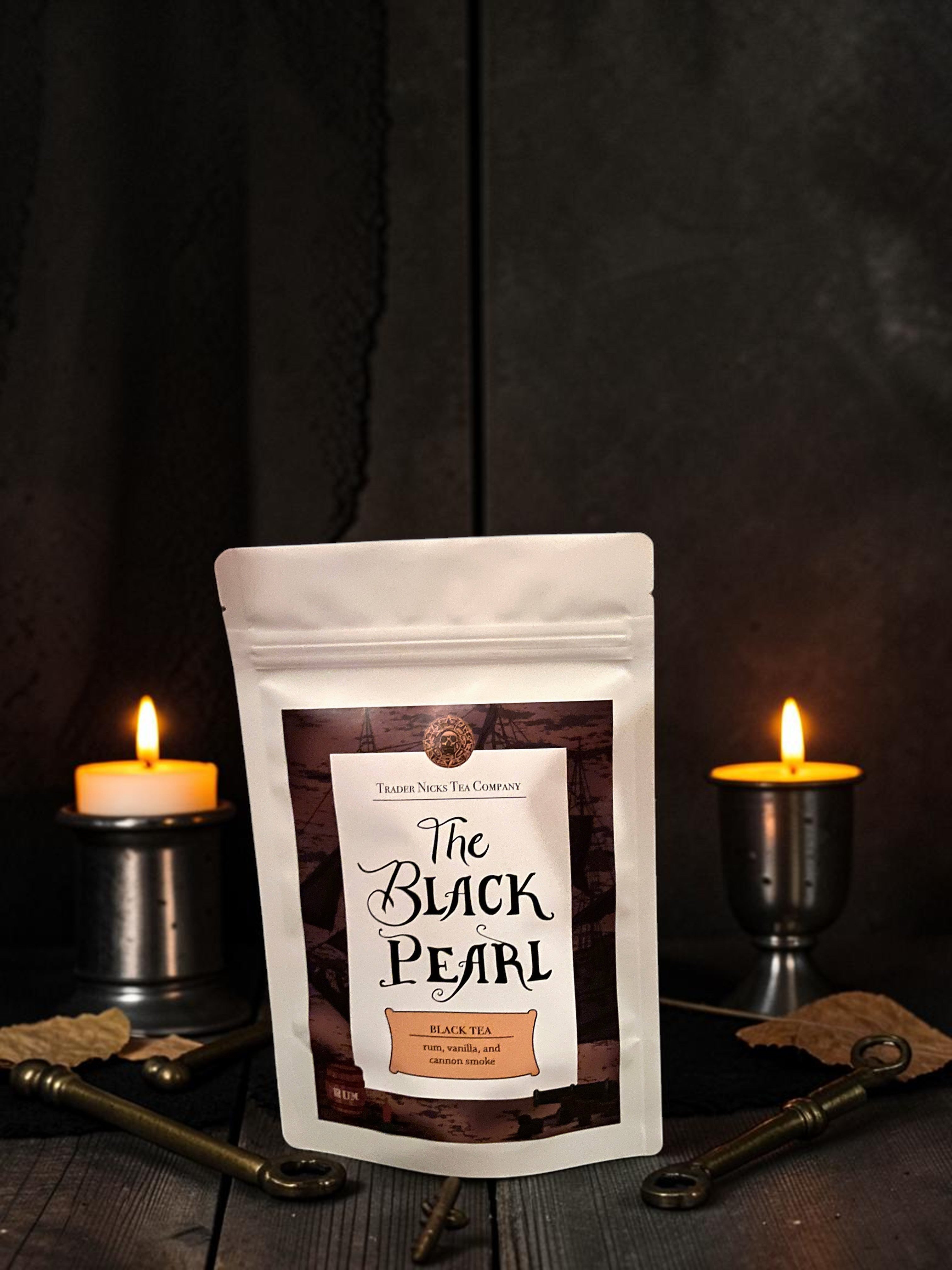 Halloween-Emporium The Black Pearl smoked black tea pouch with rum and coconut notes, displayed with candles and keys.