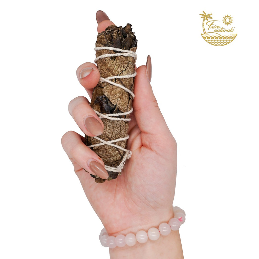 Halloween-Emporium 4-inch hand-tied black sage smudge bundle held in a hand with a rose quartz beaded bracelet