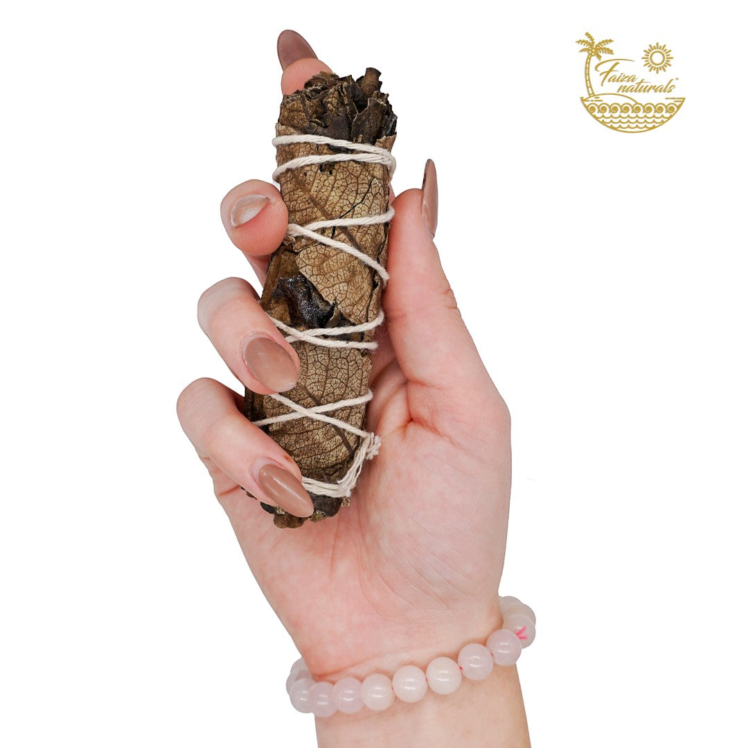 Halloween-Emporium 4-inch hand-tied black sage smudge bundle held in a hand with a rose quartz beaded bracelet