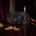 Halloween-Emporium black satin masquerade mask with a sleek finish, resting on a dark wooden table with a candle.