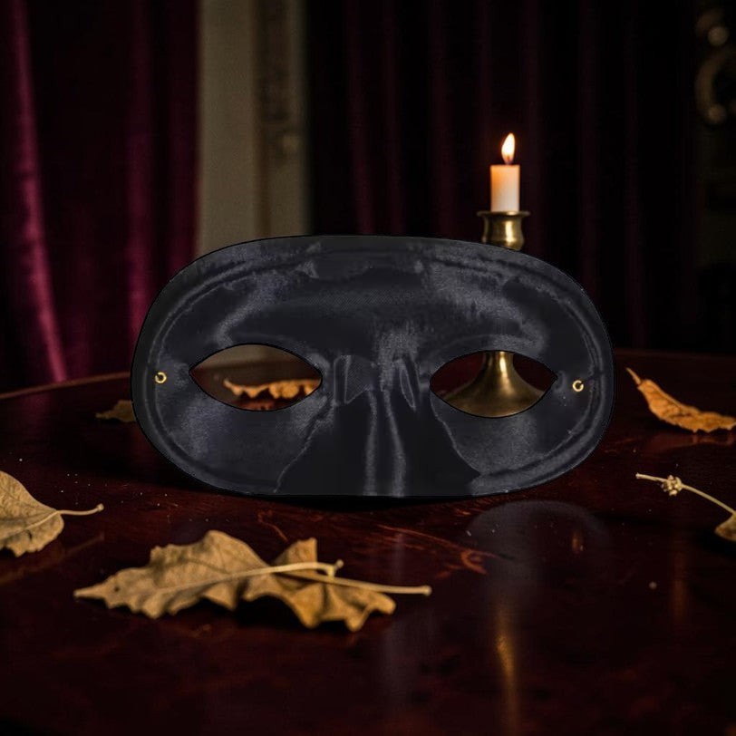 Halloween-Emporium black satin masquerade mask with a sleek finish, resting on a dark wooden table with a candle.