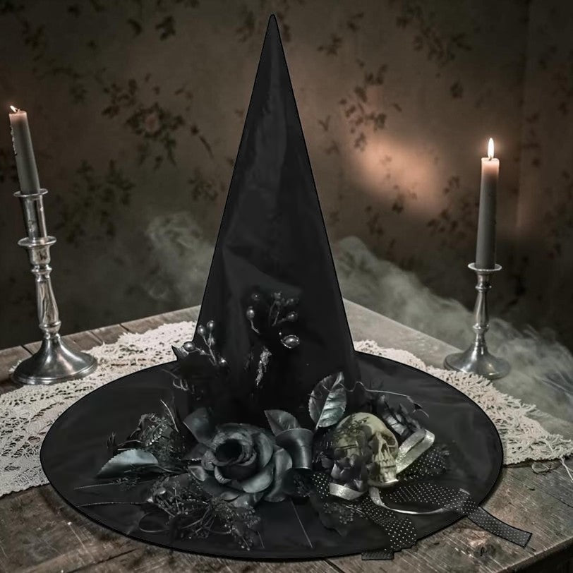 Halloween-Emporium black witch hat featuring a skull and dark gothic flowers on a table with lit candles.