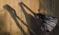 Halloween-Emporium decorative witch broomstick with a rustic gnarled handle and shimmering black tinsel bristles.
