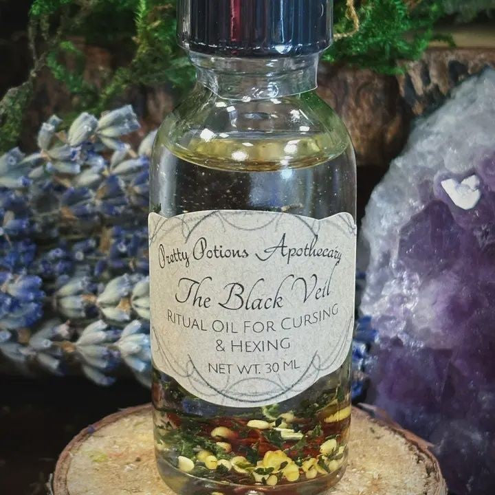 Halloween-Emporium The Black Veil ritual oil in a 30ml glass bottle with visible botanical herbs for hexing and cursing.
