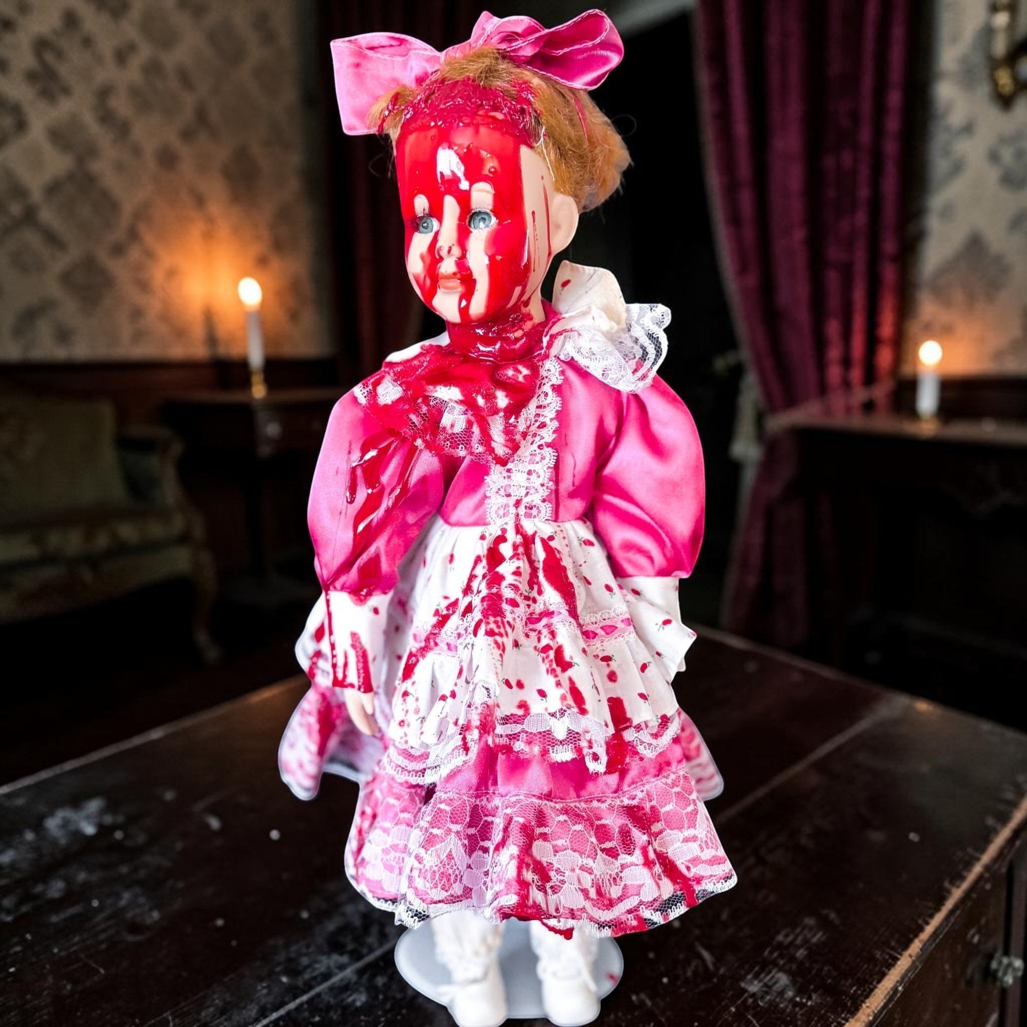 Halloween-Emporium vintage creepy doll in a pink satin dress with realistic blood splatter for horror decor