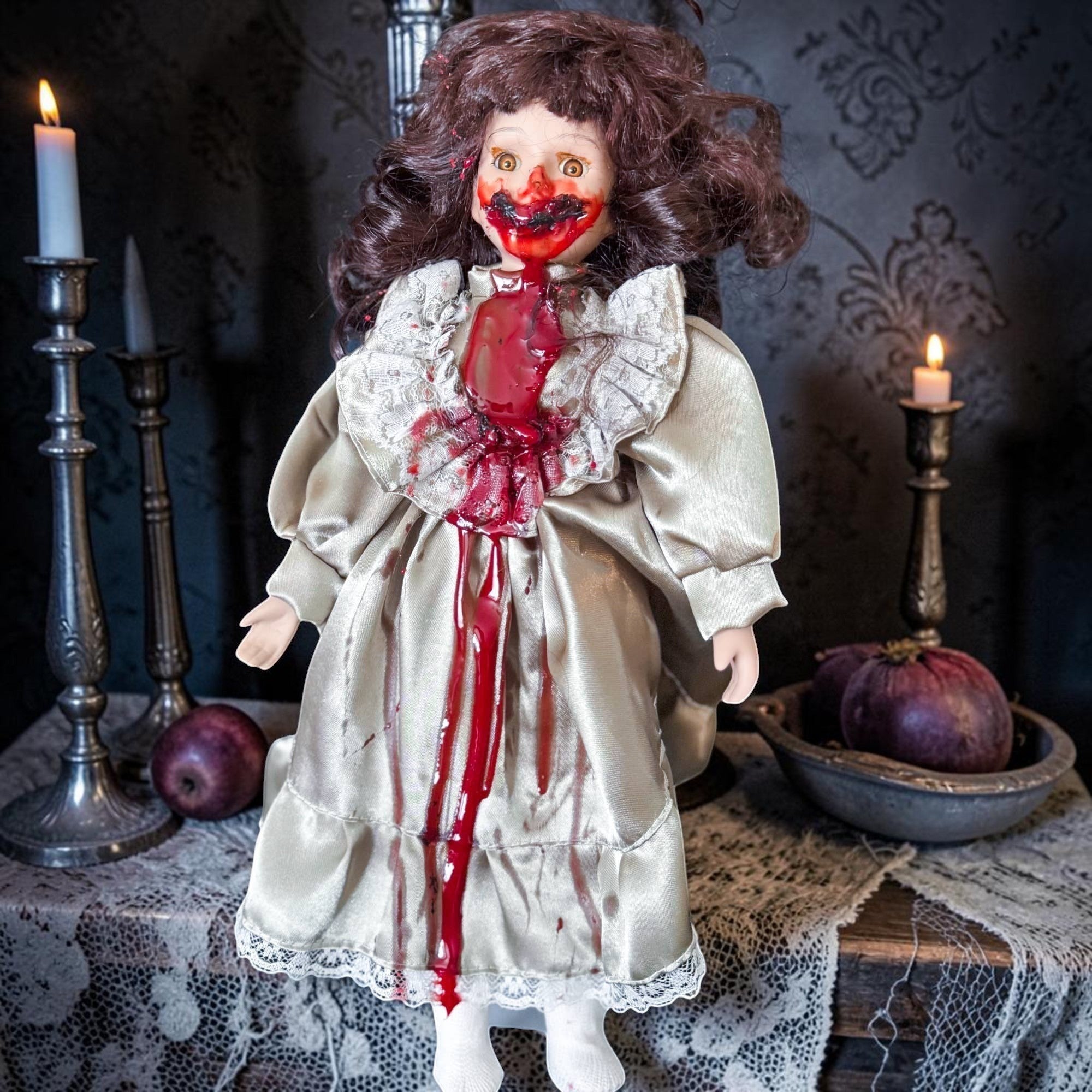 Halloween-Emporium haunted porcelain-style doll in a cream satin gown with gruesome blood splatters and lace trim.
