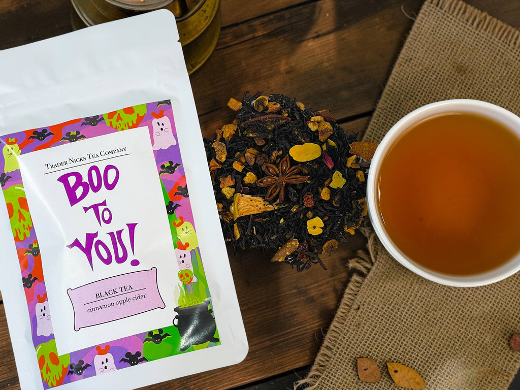 Halloween-Emporium Boo to You black tea blend with apple, spices, and a festive Halloween label next to a cup of tea.