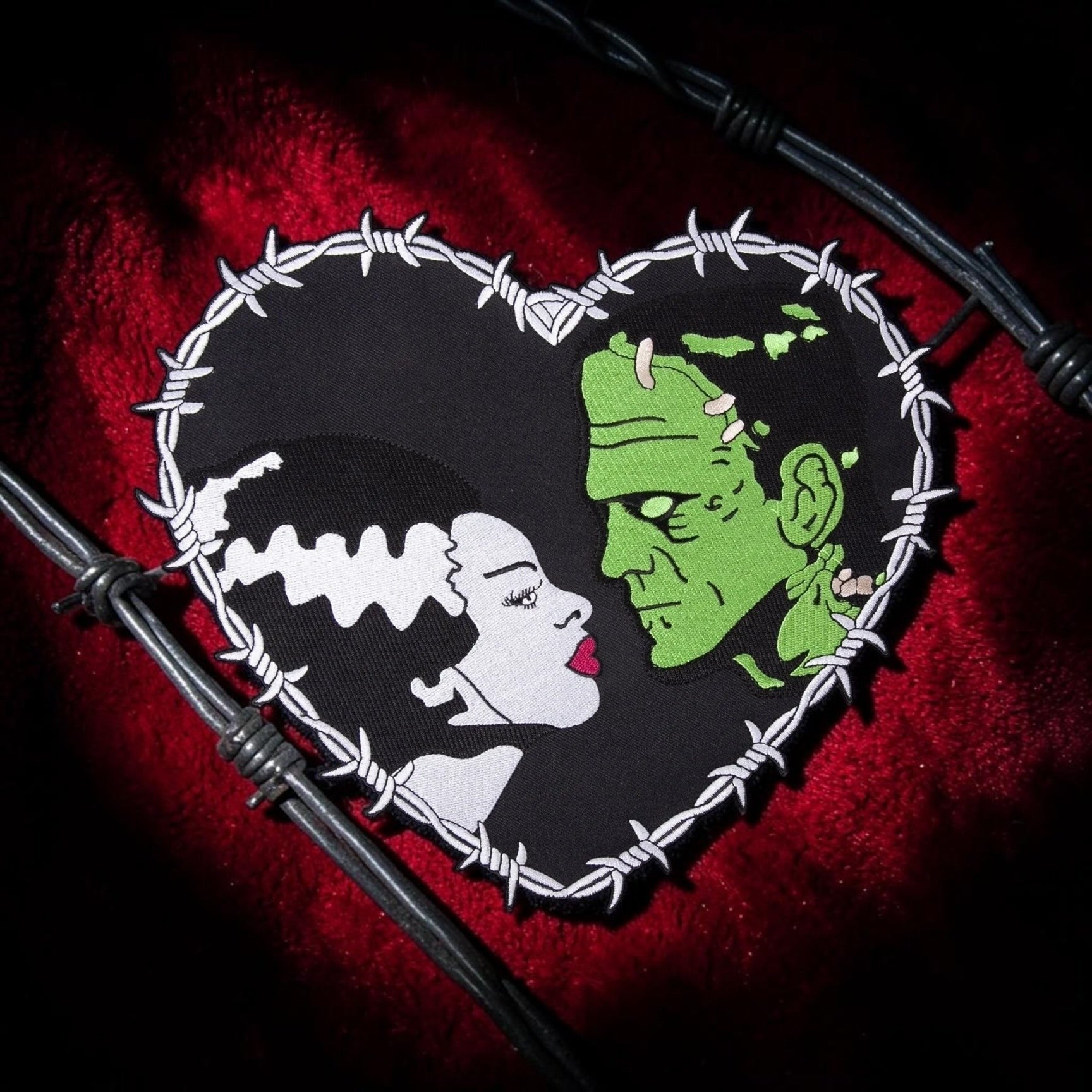Halloween-Emporium Bride and Frankenstein heart-shaped embroidered patch with barbed wire border on red velvet