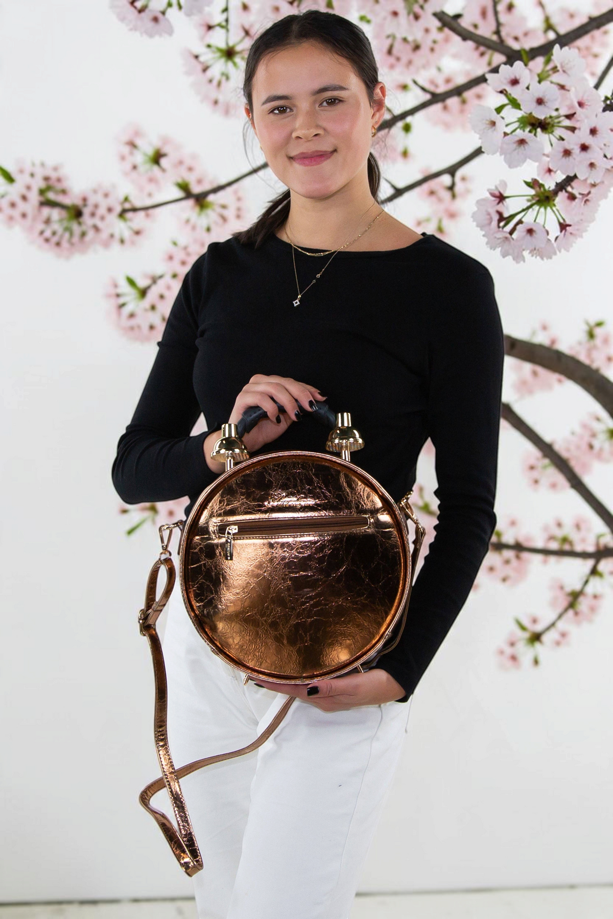 Halloween-Emporium antique clock bag in metallic bronze vinyl with a zippered pocket, held by a woman in a studio.