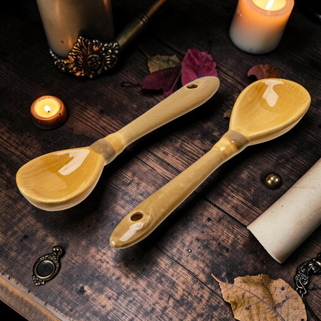 Halloween-Emporium ceramic broomstick-shaped teaspoons with a glossy tan finish on a rustic wooden table.