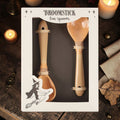 Halloween-Emporium set of two glossy tan ceramic tea spoons shaped like whimsical witch broomsticks in packaging.