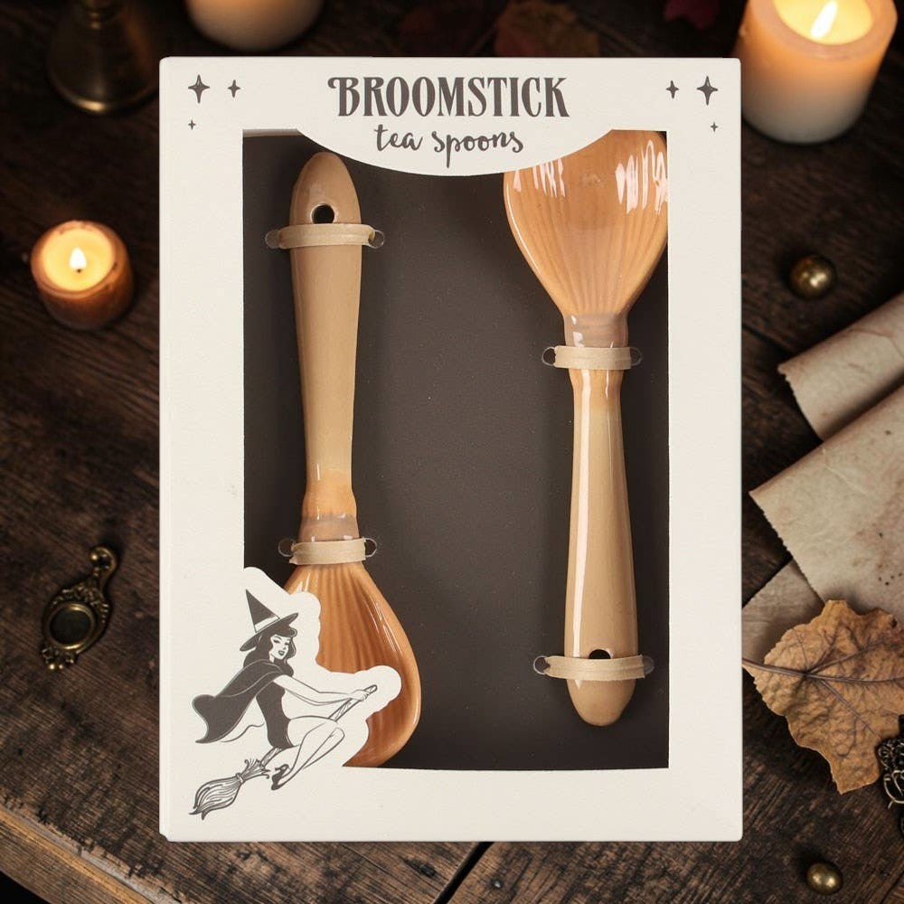 Halloween-Emporium set of two glossy tan ceramic tea spoons shaped like whimsical witch broomsticks in packaging.