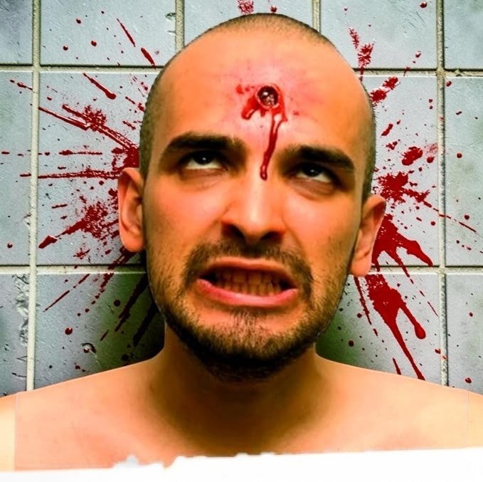Halloween-Emporium Crazy Shot FX latex bullet wound prosthetic on a man's forehead with realistic blood splatter