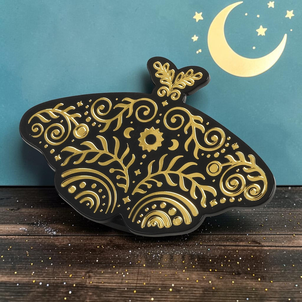 Halloween-Emporium Pantry Moths celestial bag clip in black with gold foil moth wing patterns on a wooden surface.