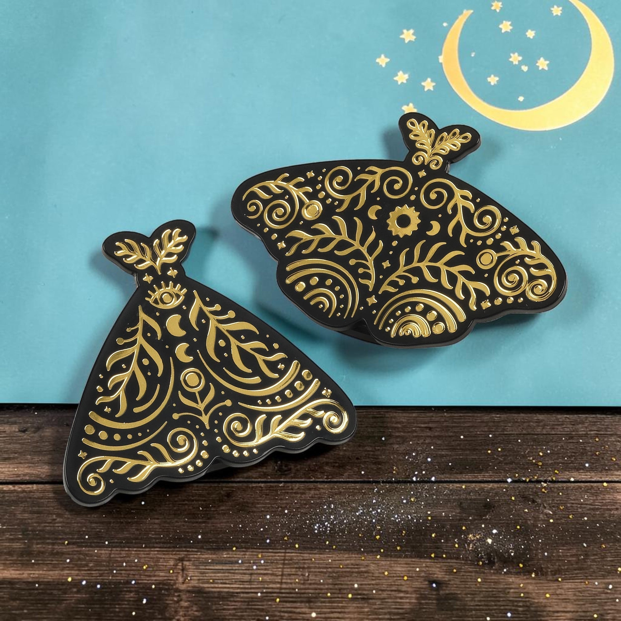 Halloween-Emporium set of two black and gold celestial moth bag clips with intricate decorative patterns