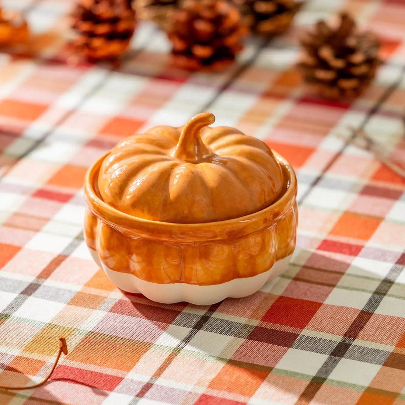 Halloween-Emporium orange and white ceramic pumpkin serving dish with lid on a plaid autumn tablecloth