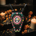 Halloween-Emporium coffin-shaped convertible backpack in black vinyl with colorful Dia de los Muertos sugar skull art.
