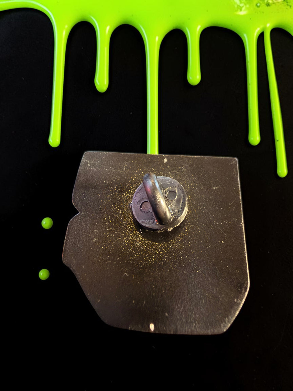 Halloween-Emporium Colin Robinson enamel pin back view with metal clutch against a black background with green slime