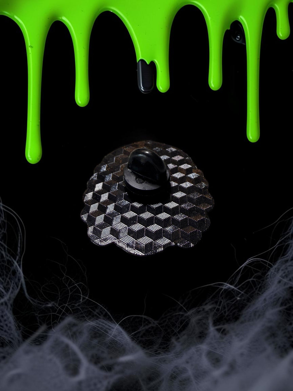 Halloween-Emporium Creature enamel pin back view showing the black rubber clutch on a black surface with green slime.