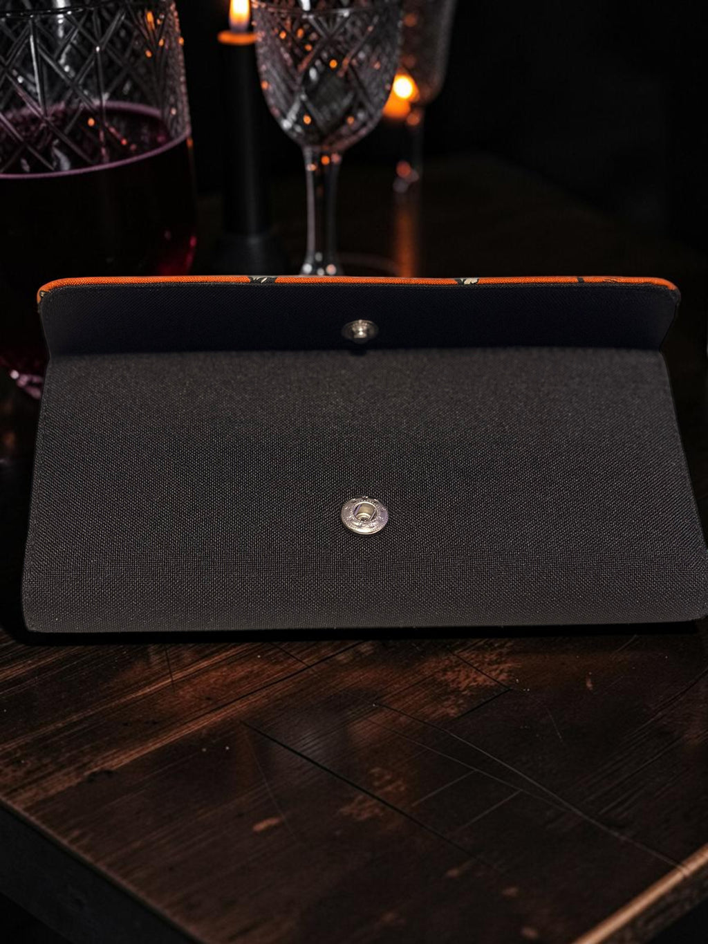 Halloween-Emporium Deadly Apothecary clutch wallet in black with a snap closure on a dark wooden table