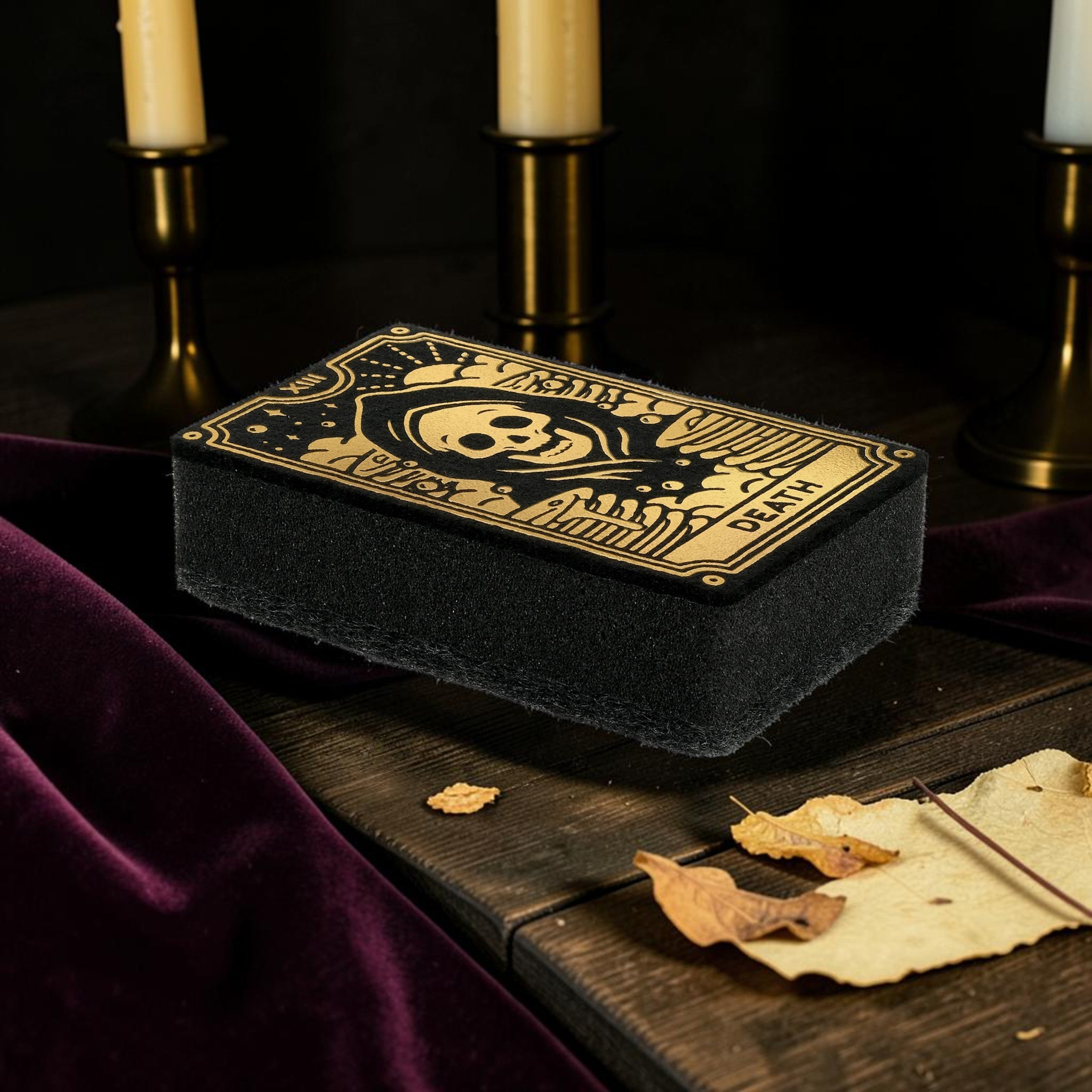 Halloween-Emporium Death tarot card kitchen sponge with metallic gold skull illustration on a dark wooden table.