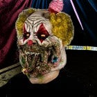 Halloween-Emporium Charles Demon of Gluttony latex clown mask with yellow hair, grotesque details, and a cupcake topper.