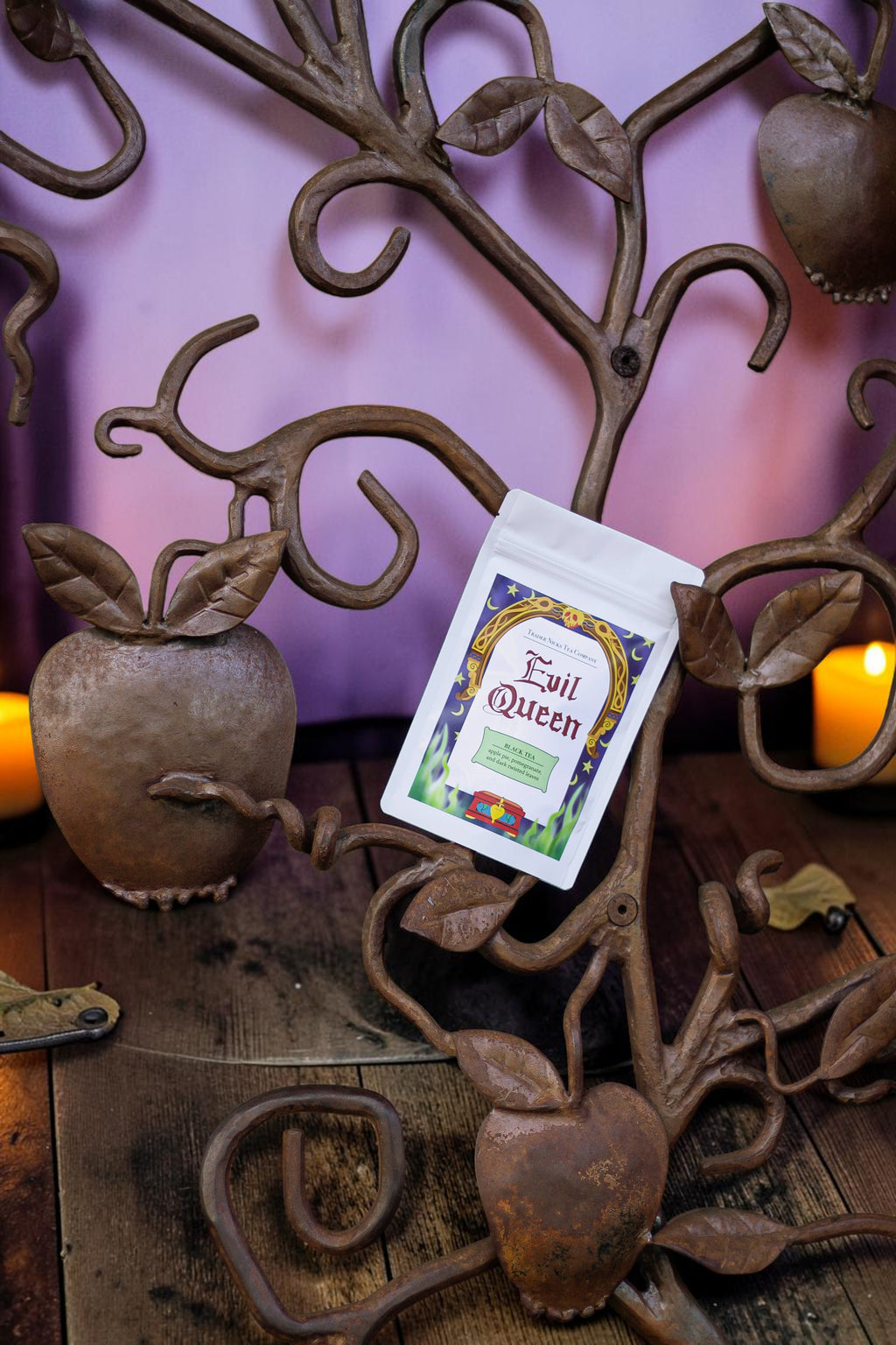 Halloween-Emporium Evil Queen Spiced Apple black tea pouch displayed on a decorative iron apple tree sculpture.