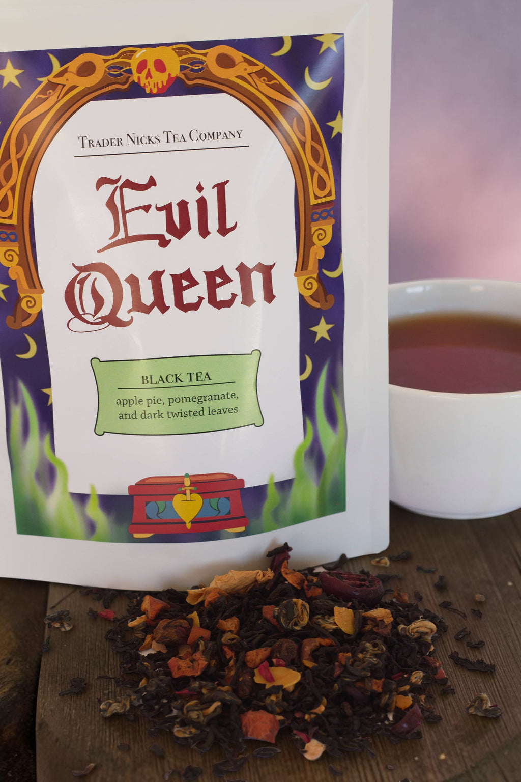 Halloween-Emporium Evil Queen spiced apple black tea blend with fruit pieces and rolled tea leaves next to a cup.