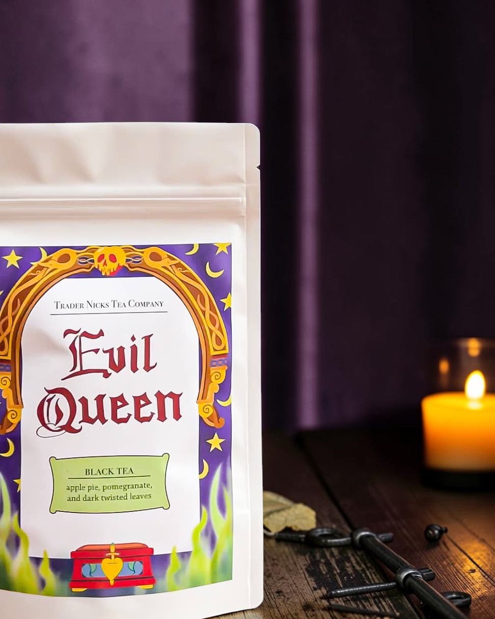Halloween-Emporium Evil Queen spiced apple black tea pouch with villain-themed label on a dark table with a candle.
