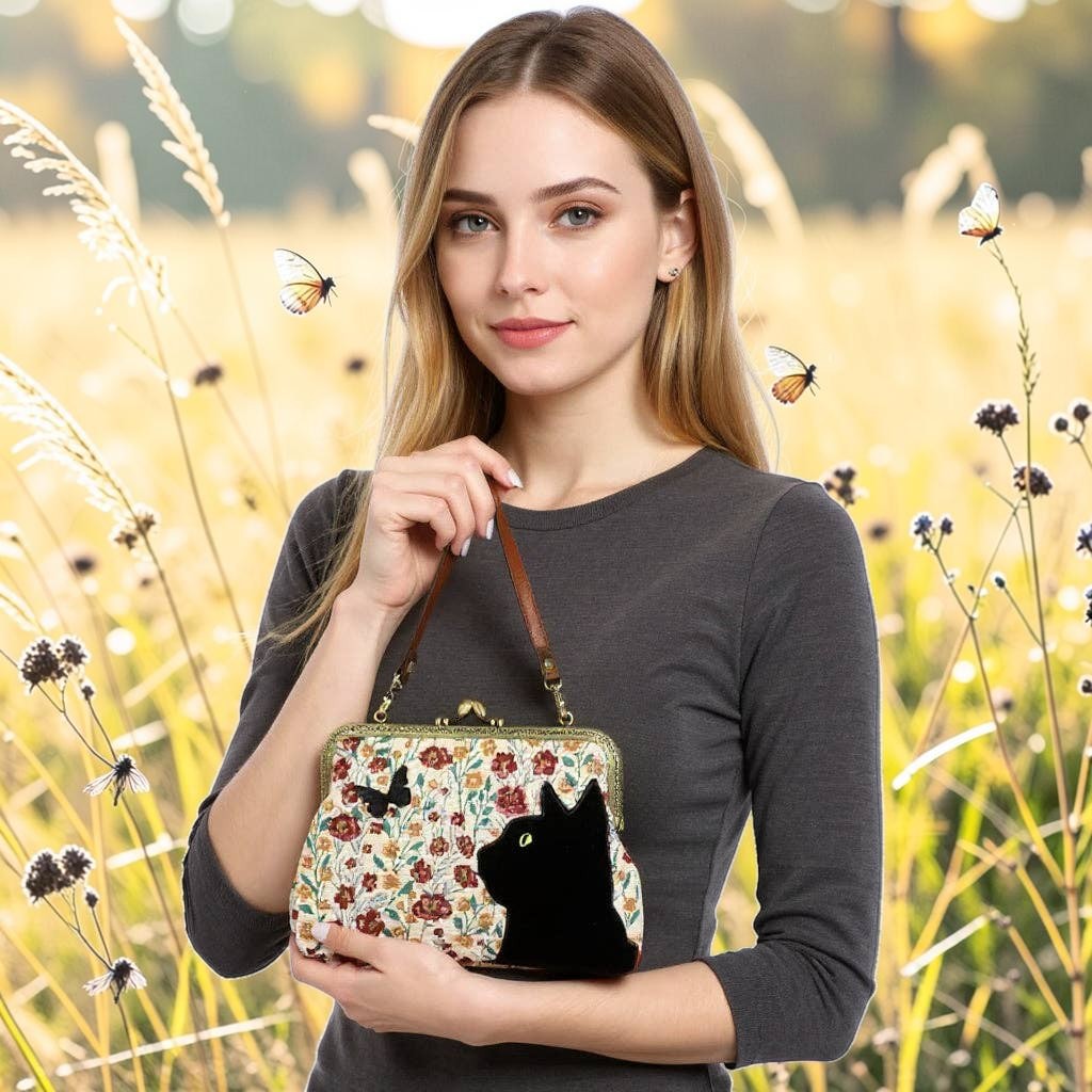 Halloween-Emporium floral kisslock bag with black cat and butterfly velvet appliqué held by a woman in a field.