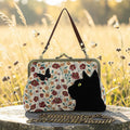 Halloween-Emporium floral kisslock bag featuring a black velvet cat and butterfly appliqué in a grassy field