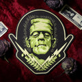 Halloween-Emporium large Frankenstein embroidered iron-on patch with green monster face and lightning bolt details.