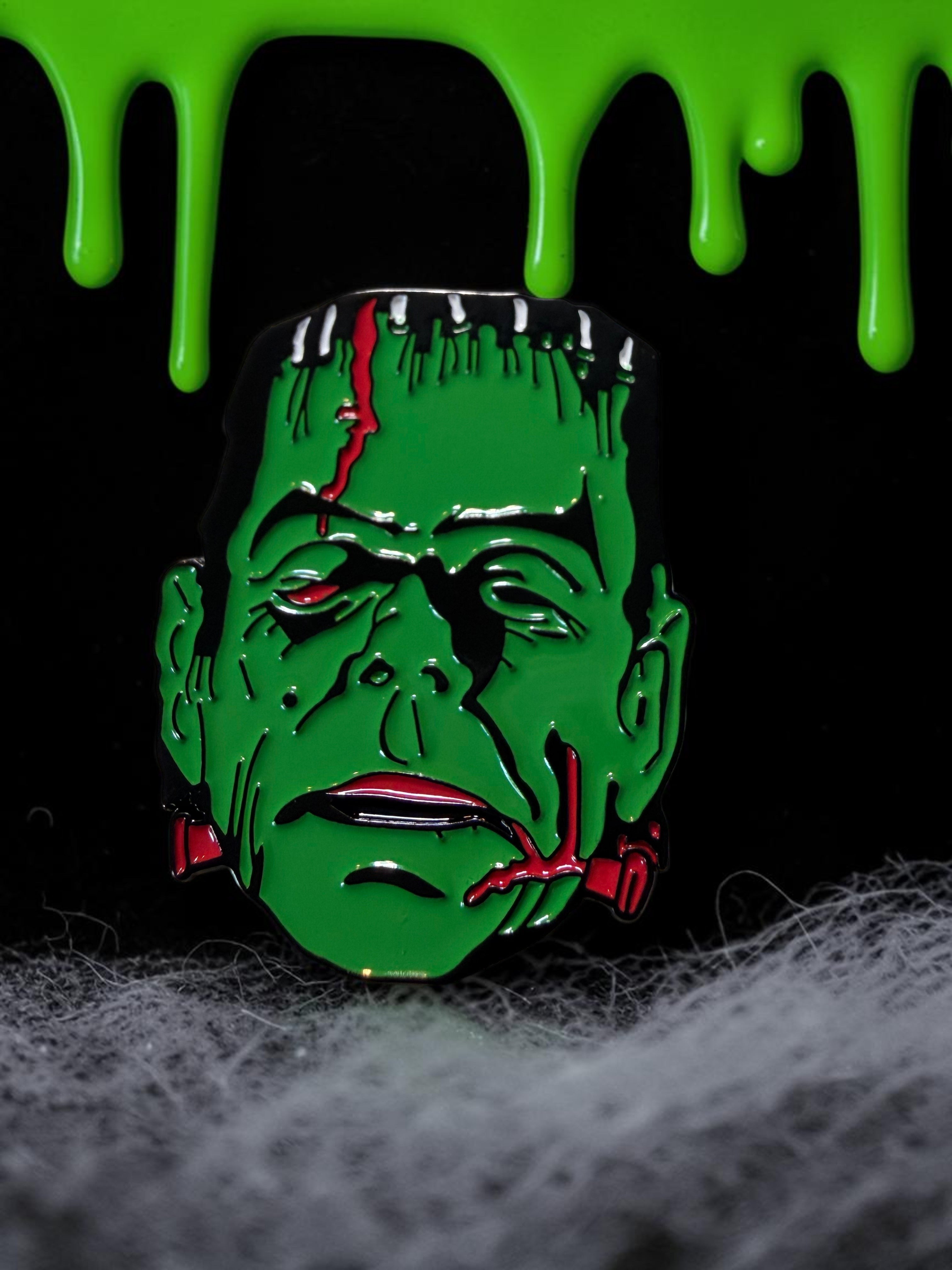 Halloween-Emporium pop art Frankenstein enamel pin featuring vibrant green skin and red details on a spooky background