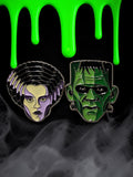 Halloween-Emporium Bride of Frankenstein and Frankenstein's monster soft enamel pins on a spooky black background.