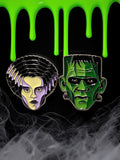 Halloween-Emporium enamel pins featuring Frankenstein's Monster and the Bride of Frankenstein on a black background.