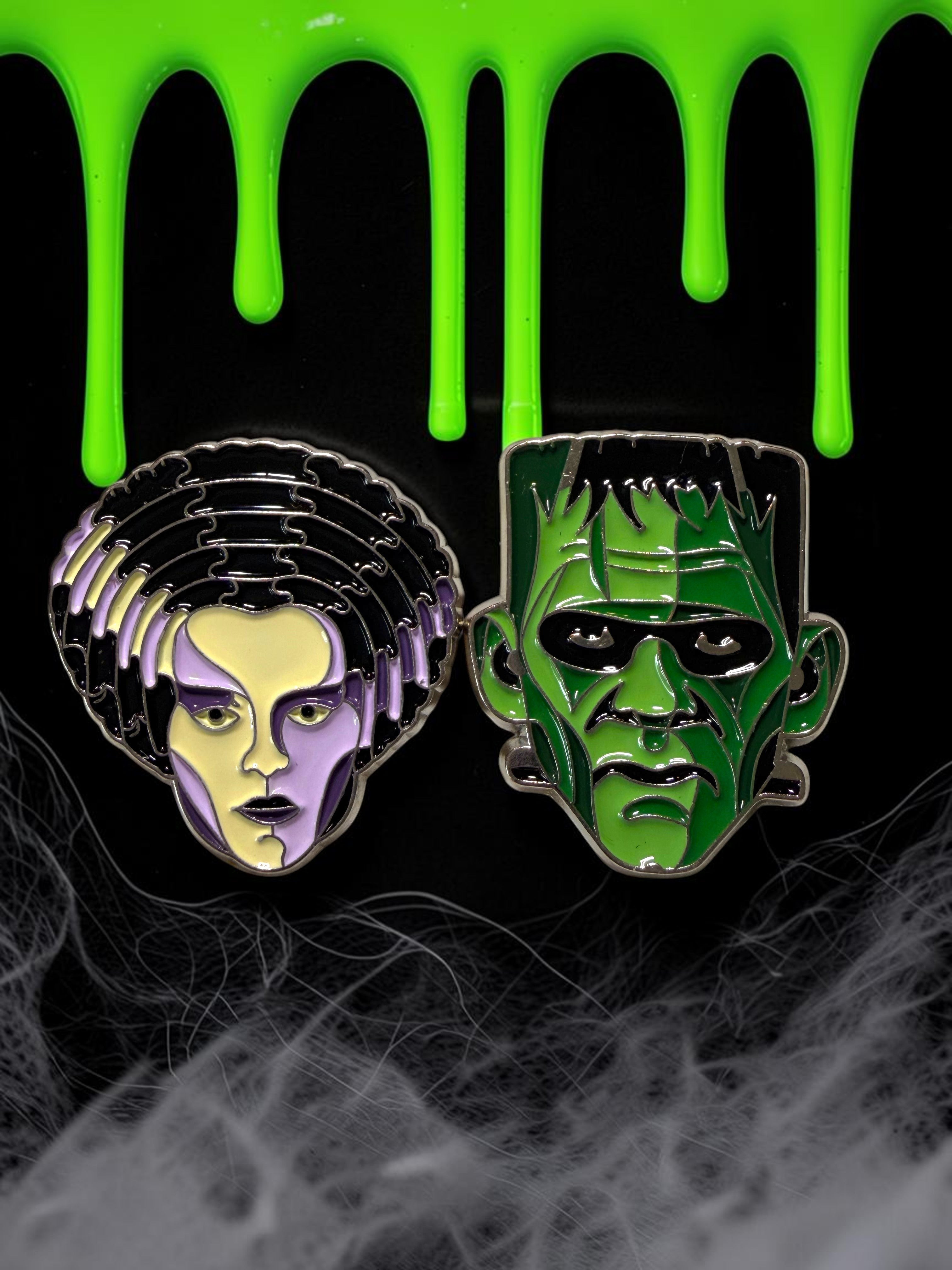 Halloween-Emporium enamel pins featuring Frankenstein's Monster and the Bride of Frankenstein on a black background.